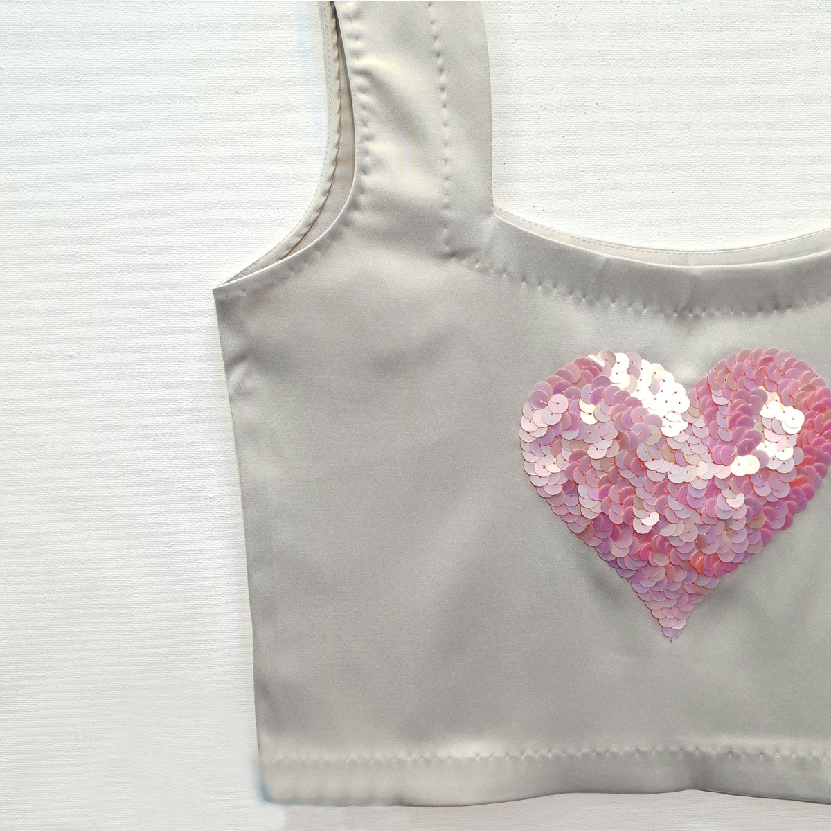 Top corto in raso duchessa grigio argento con ricamo a forma di cuore in paillettes
