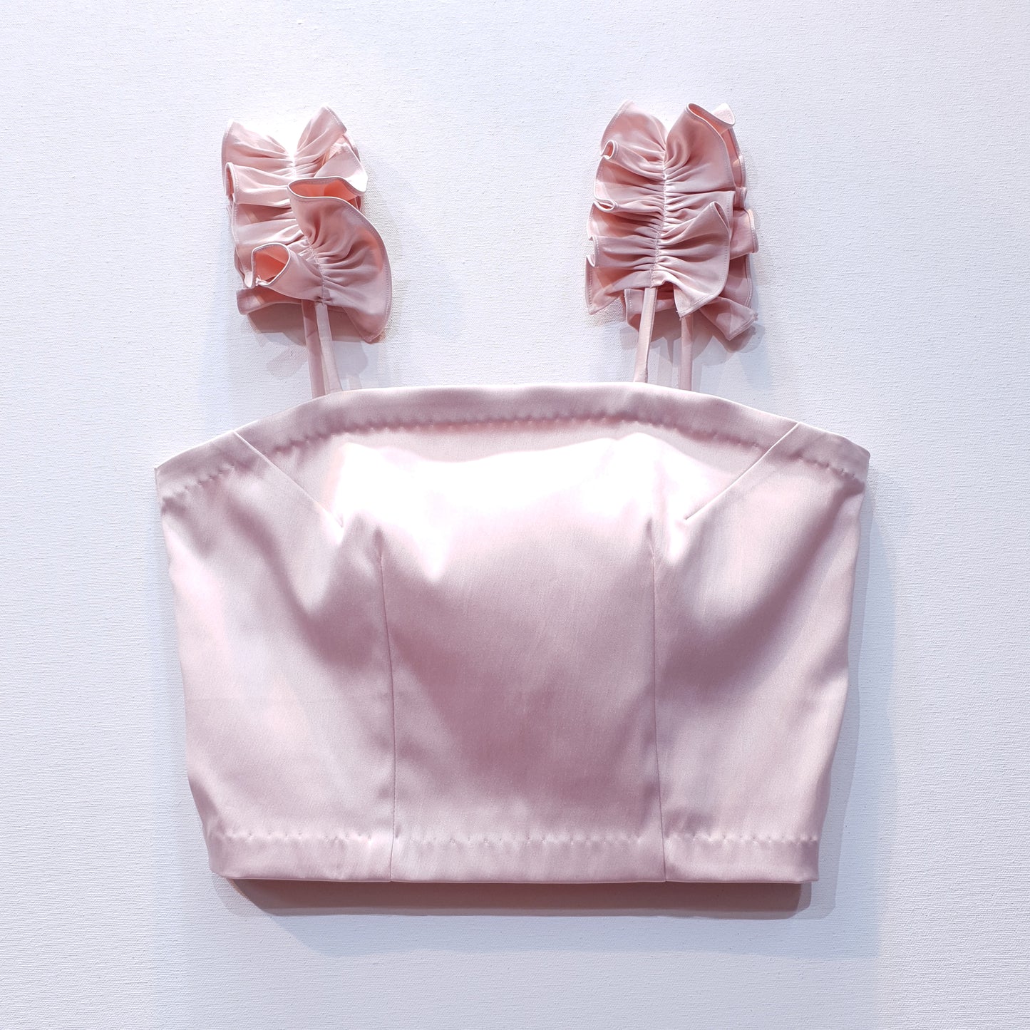Pink duchess satin top with ruffle straps on a white background