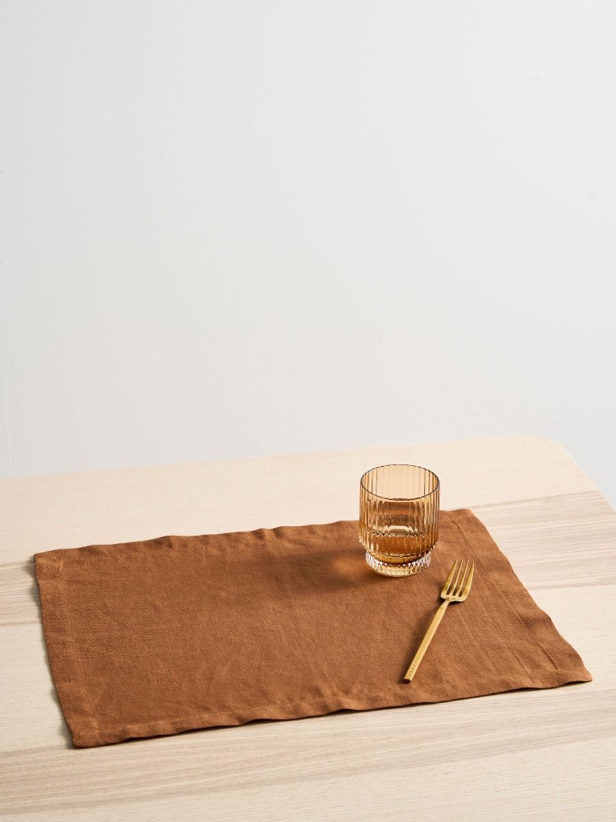 Brown placemat with a glass and fork on a wooden surface
