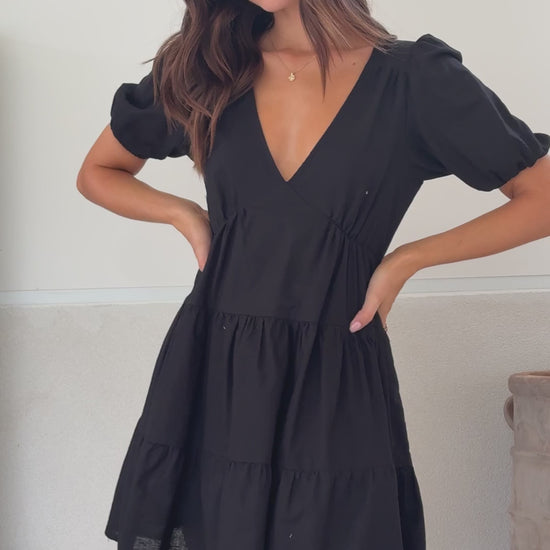 Black linen mini dress with tiered skirt, puff sleeves, and V-neckline