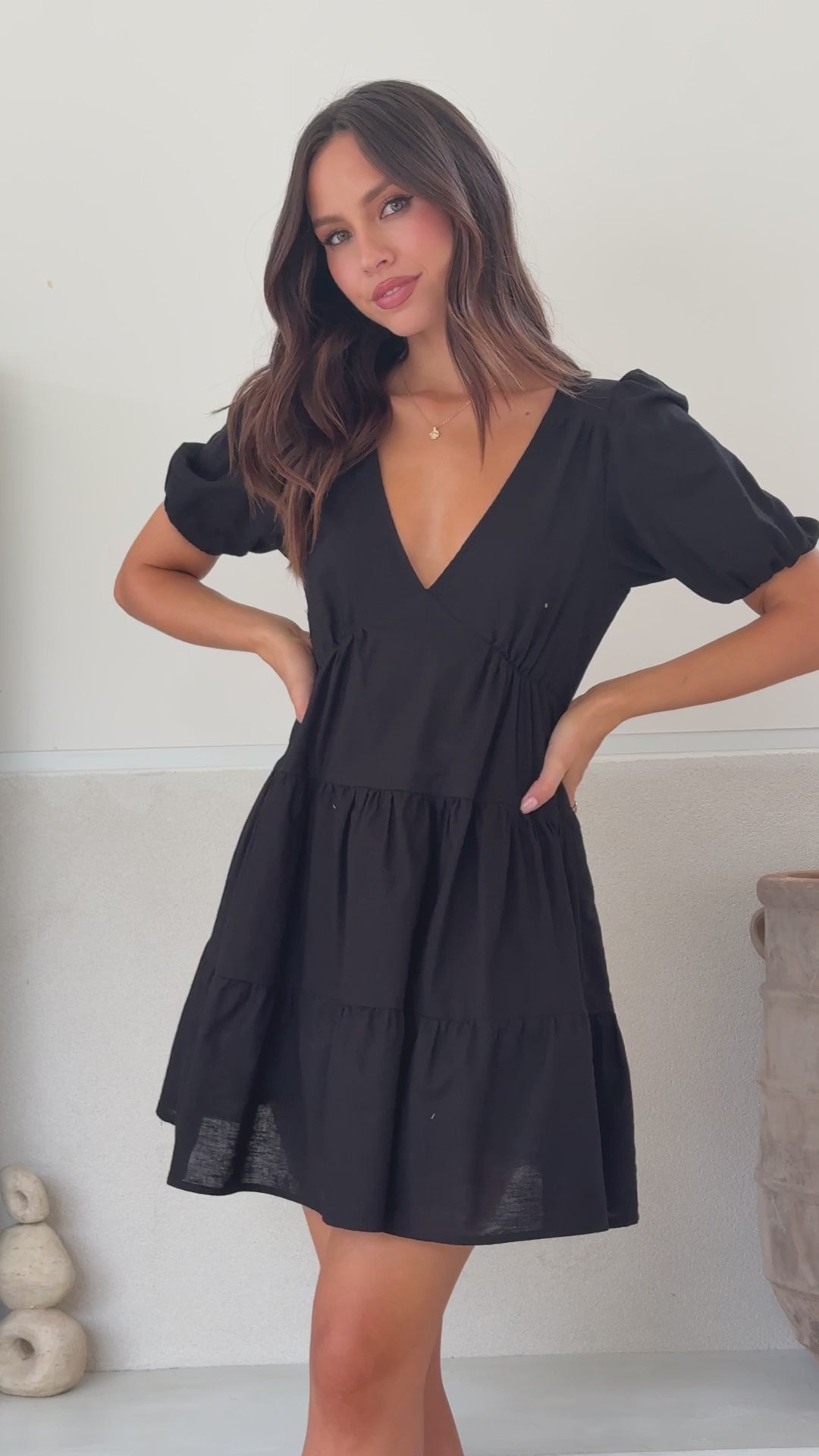Black linen mini dress with tiered skirt, puff sleeves, and V-neckline