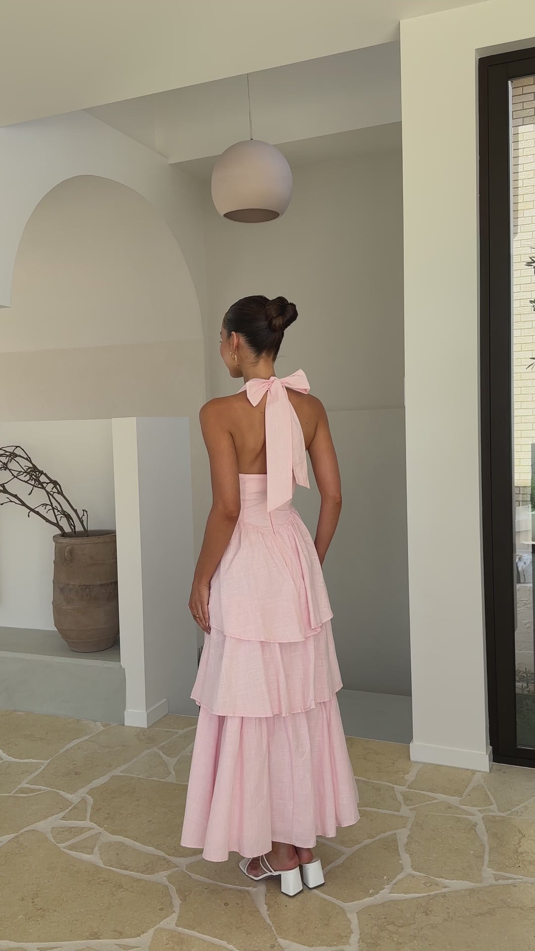 Pink crepe tiered maxi dress with halter neckline and tie-up bow back