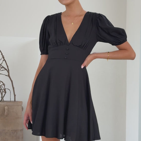 Black linen mini dress with puff sleeves, V-neckline, and flared skirt