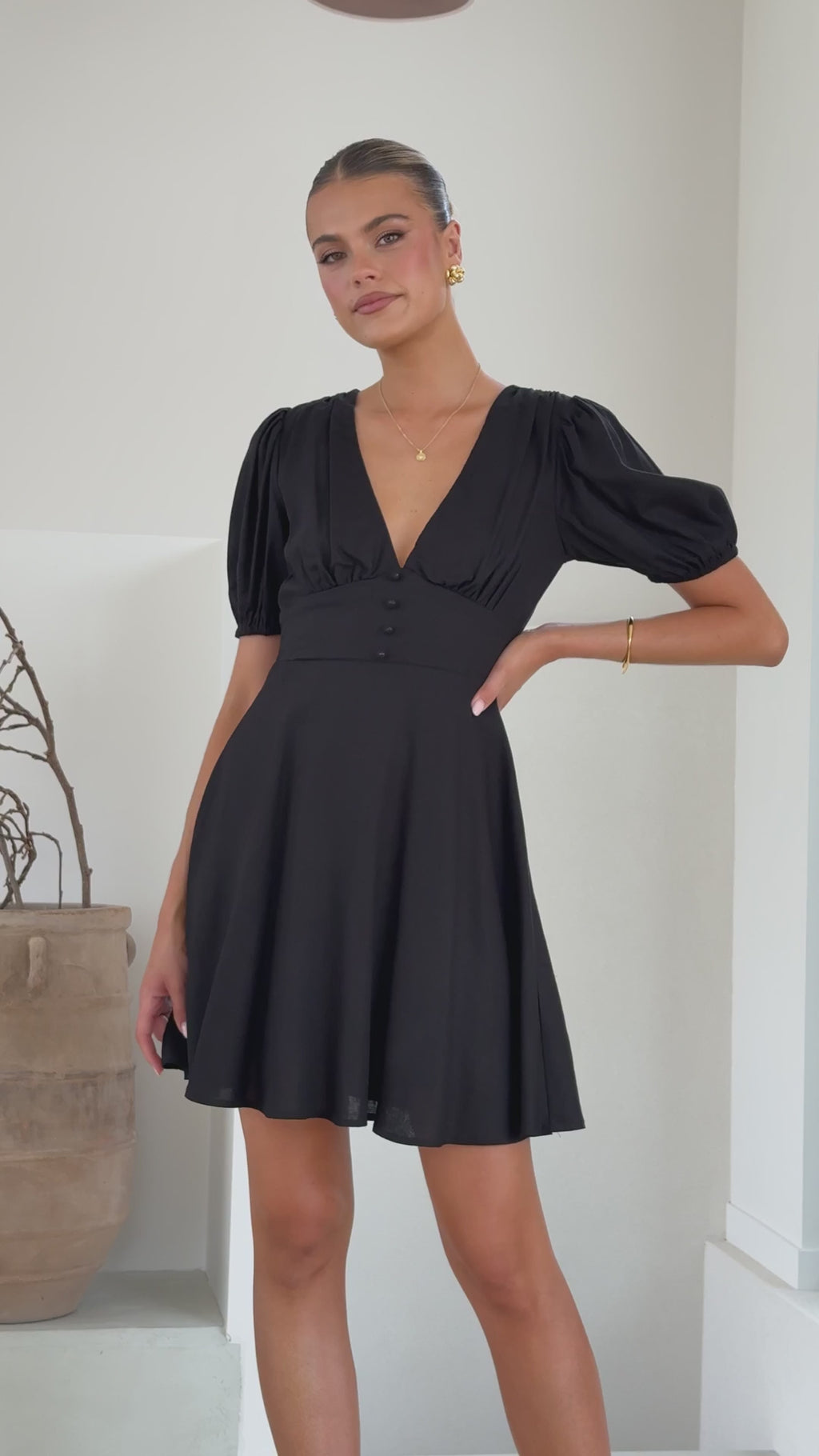 Black linen mini dress with puff sleeves, V-neckline, and flared skirt