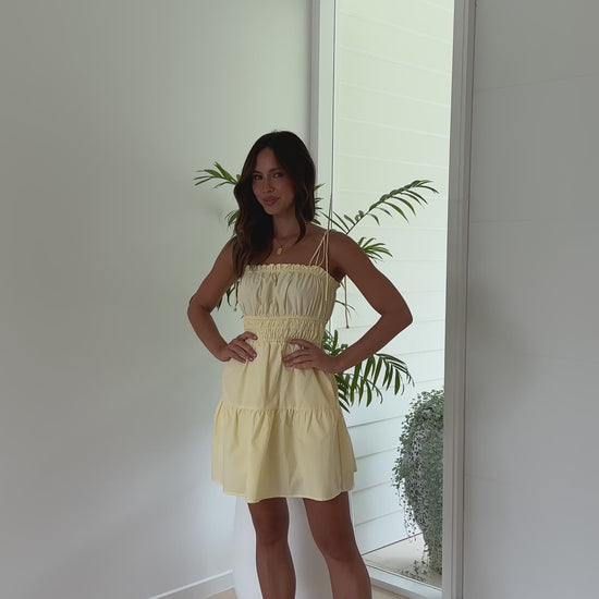 Lemon yellow cotton mini dress with smocked waist, tie straps, and pockets