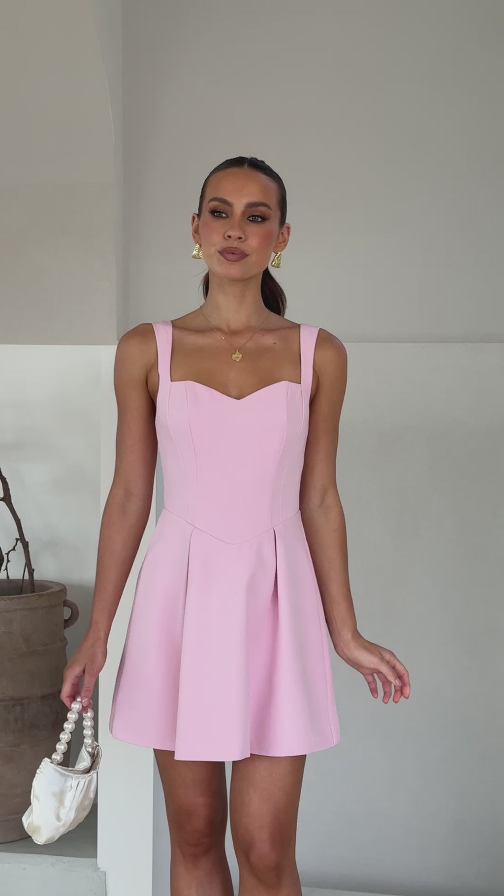 A model wearing a baby pink mini dress made of banana crepe fabric with a sweetheart neckline and a full skirt.