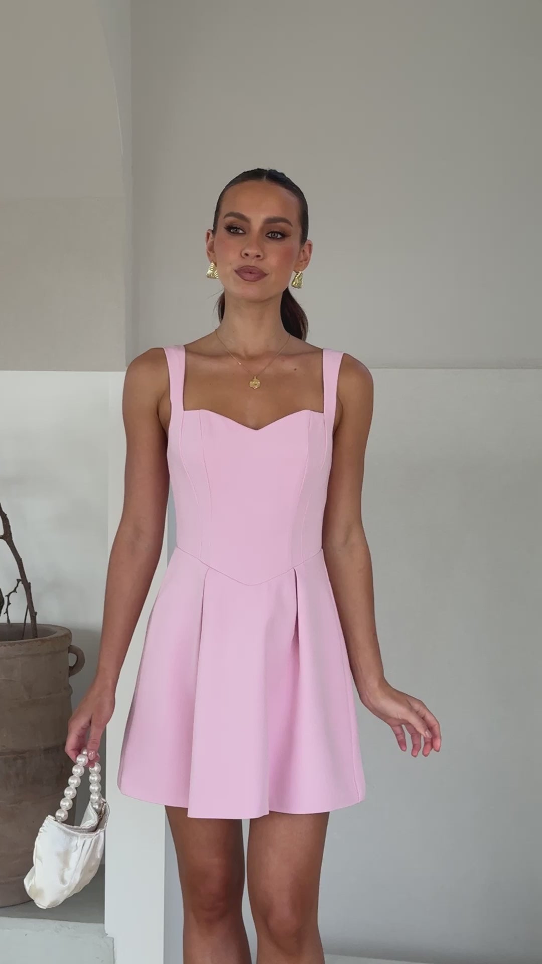 A model wearing a baby pink mini dress made of banana crepe fabric with a sweetheart neckline and a full skirt.