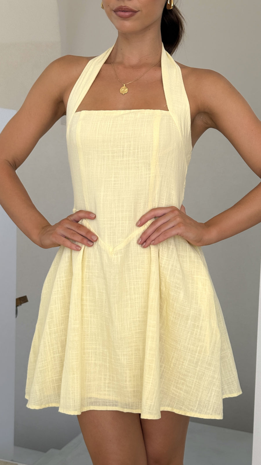 Butter yellow linen mini dress with halter straps, flared skirt, and smocked back