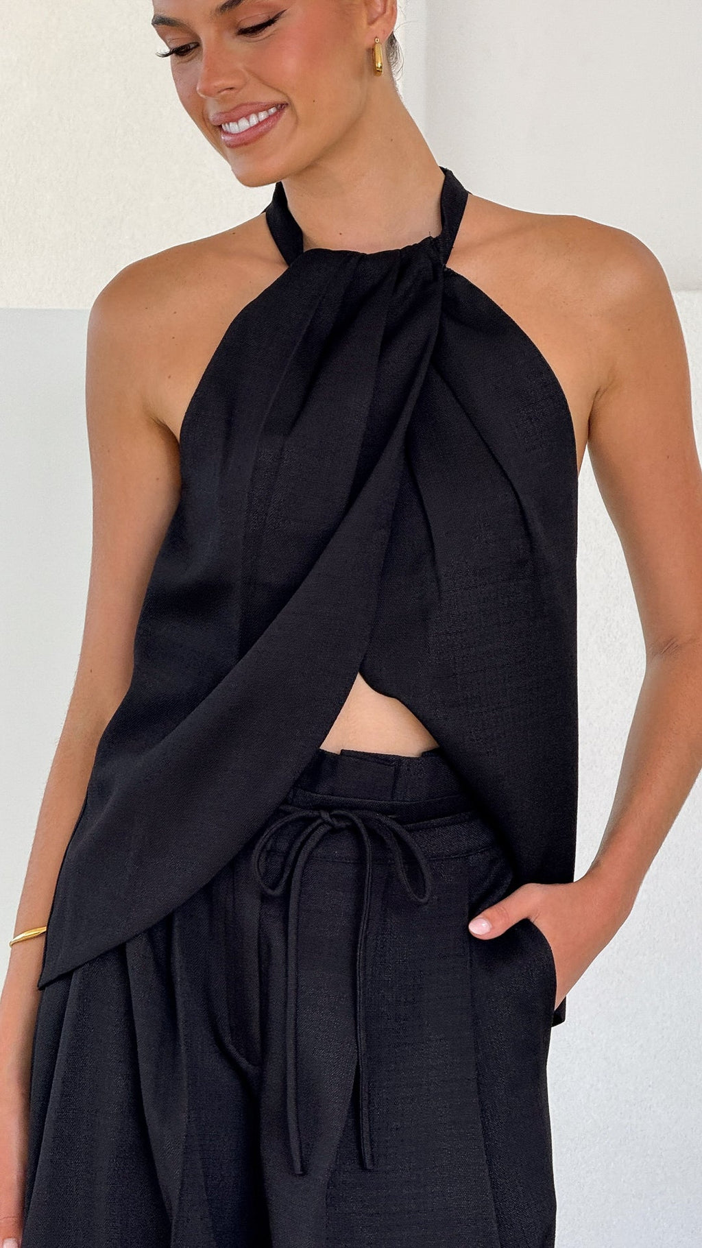 Model wearing black crepe halter top with draped neckline and open back

