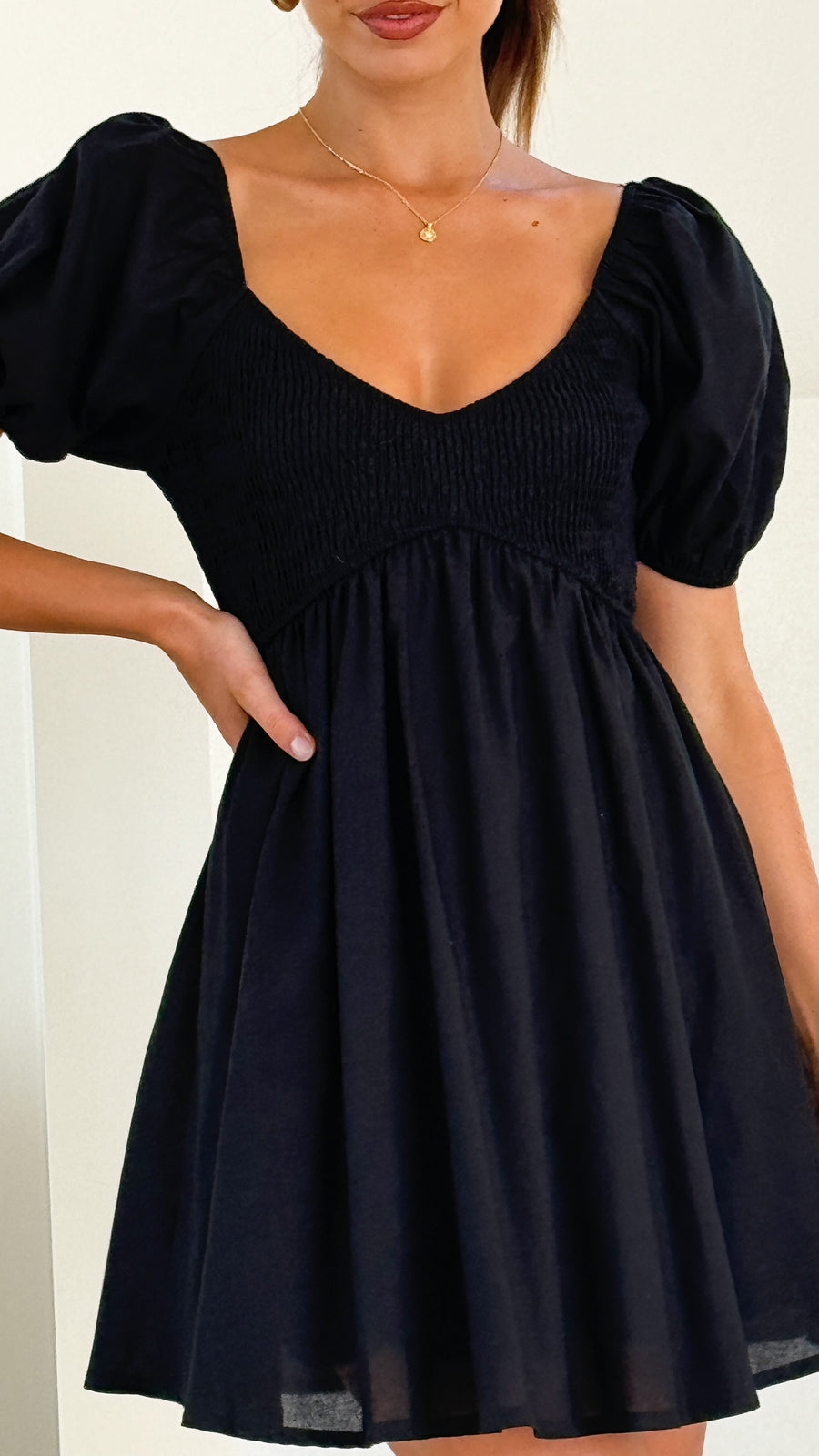 Black linen mini dress with puff sleeves, sweetheart neckline, and smocked back