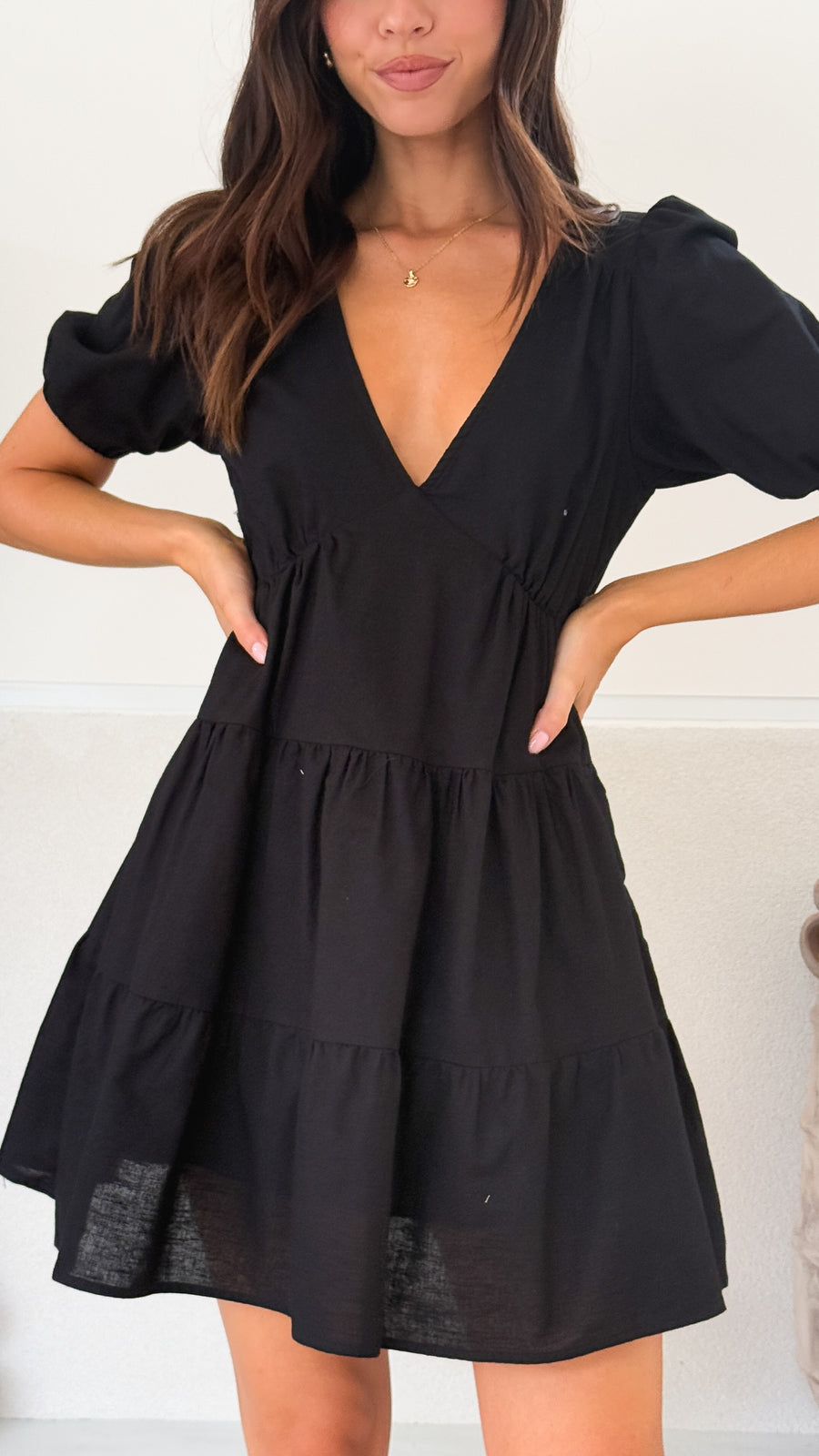 Black linen mini dress with tiered skirt, puff sleeves, and V-neckline
