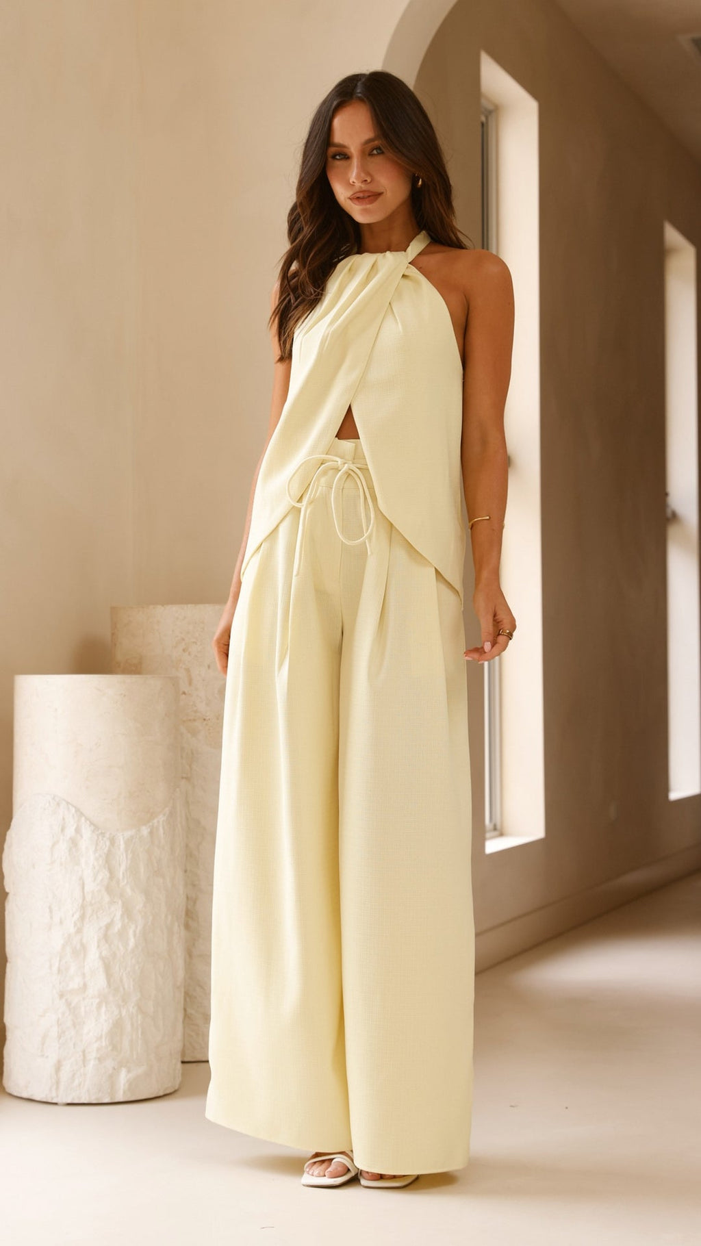 Model wearing butter yellow crepe halter top with front drape and open back