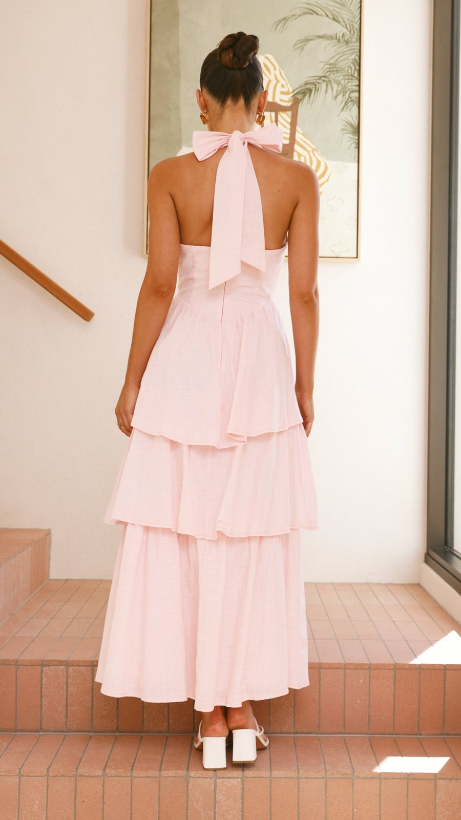 Pink crepe tiered maxi dress with halter neckline and tie-up bow back