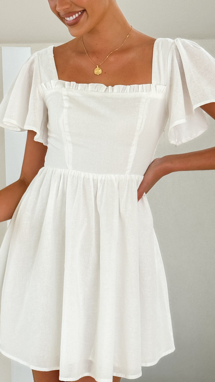 White linen mini dress with flutter sleeves, square neckline